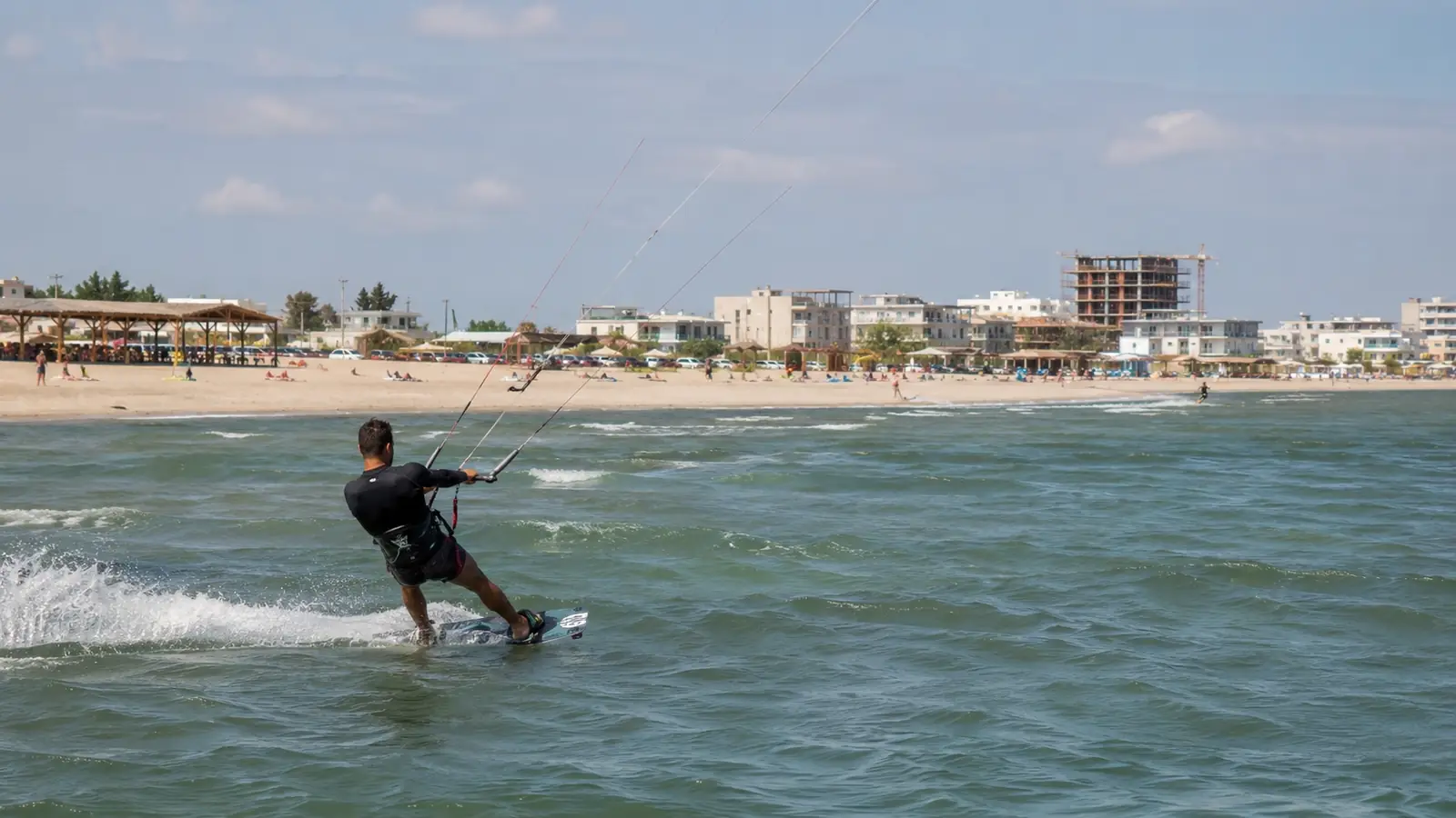 Rider de kitesurfing pe apă în dreptul plajei aglomerate din Mamaia Nord